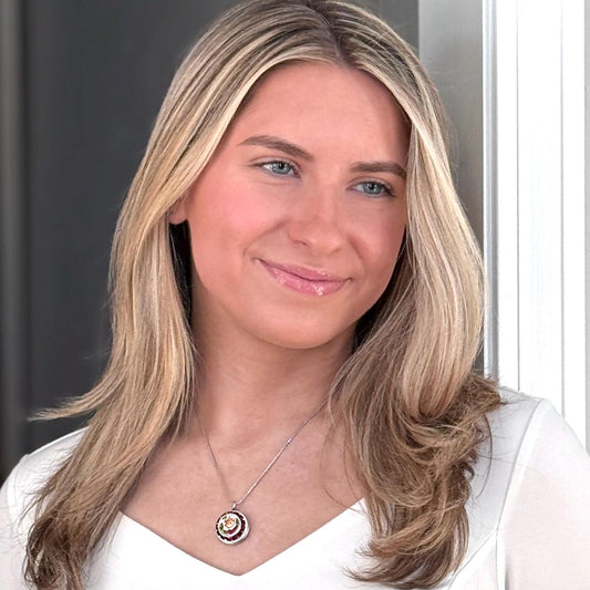 May include: A silver chain necklace with a round pendant featuring a multi-colored swirl design with red, yellow, and white gemstones.