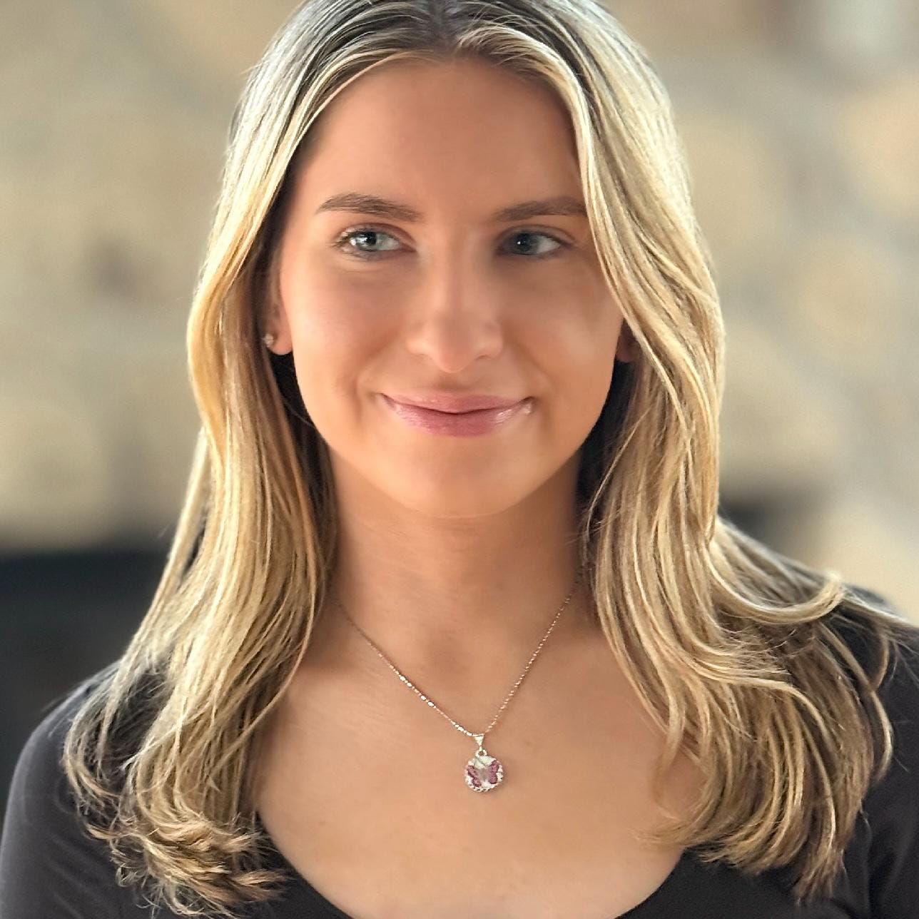 May include: A silver necklace with a round pendant featuring a dainty 5/8"pink porcelain butterfly. The woman in the image is wearing a black top and has blonde hair.